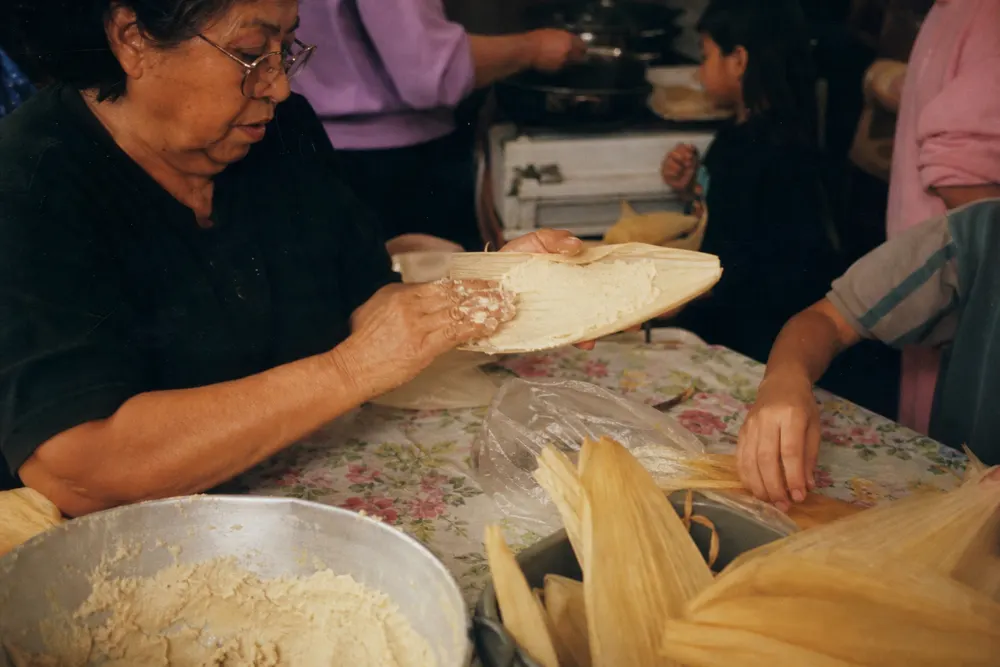 Hands making tamales at a family kitchen table
